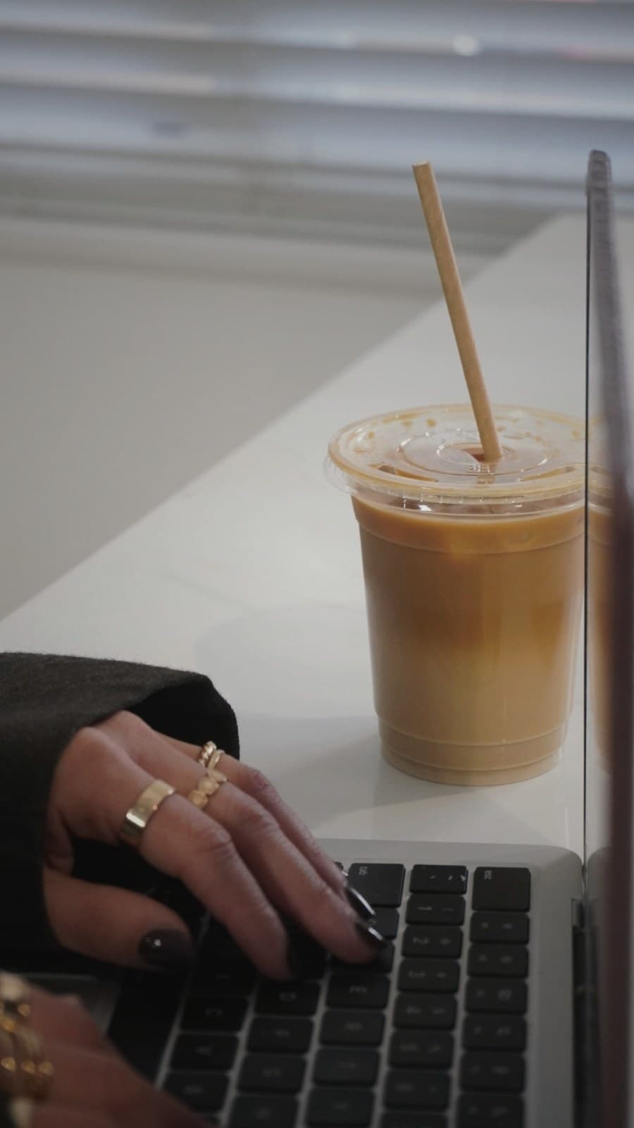 A minimalist workspace with a laptop, a notebook, and an iced coffee placed in easy reach.
